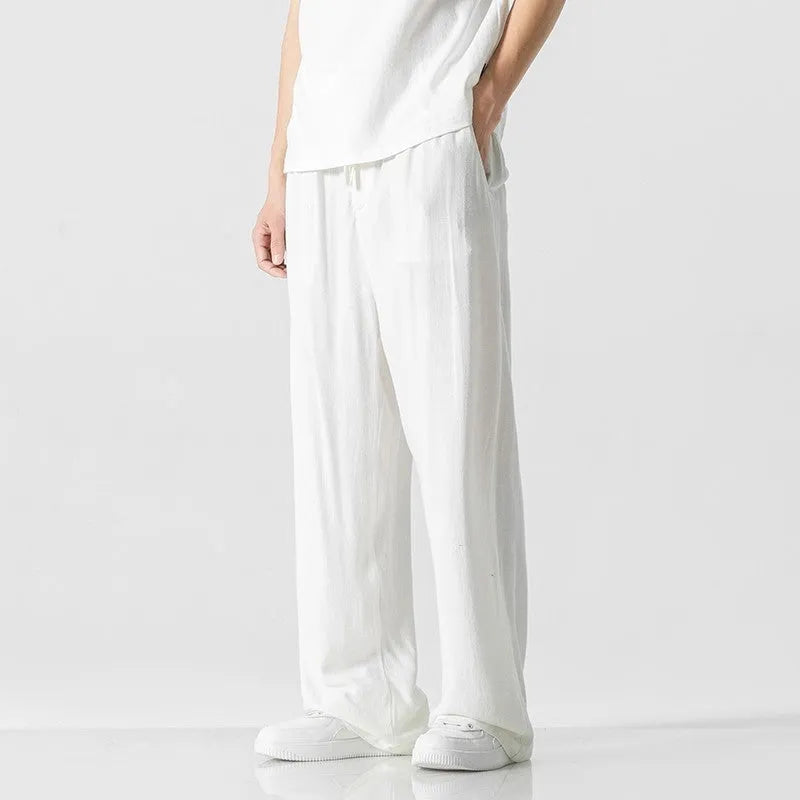 Men's beige loose straight-leg linen trousers with a drawstring waist on a neutral background.
