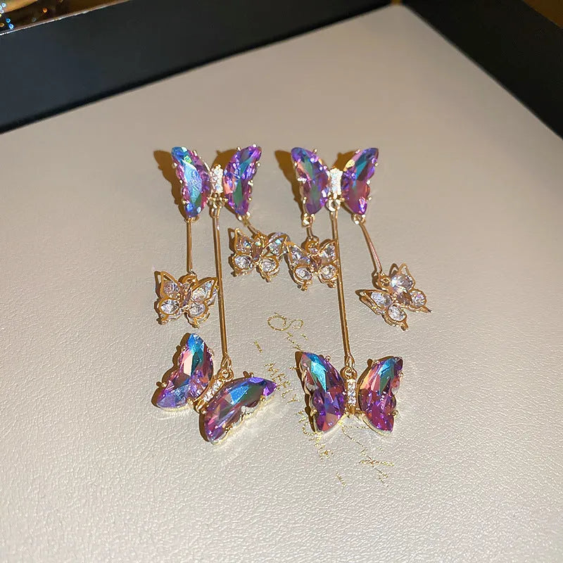 Close-up of women's silver needle blue purple butterfly alloy earrings with crystal flowers and a dangle tassel.
