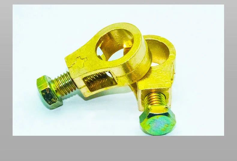 Solid copper car battery cable terminal clamp with brass bolts and a black plastic protective cover.