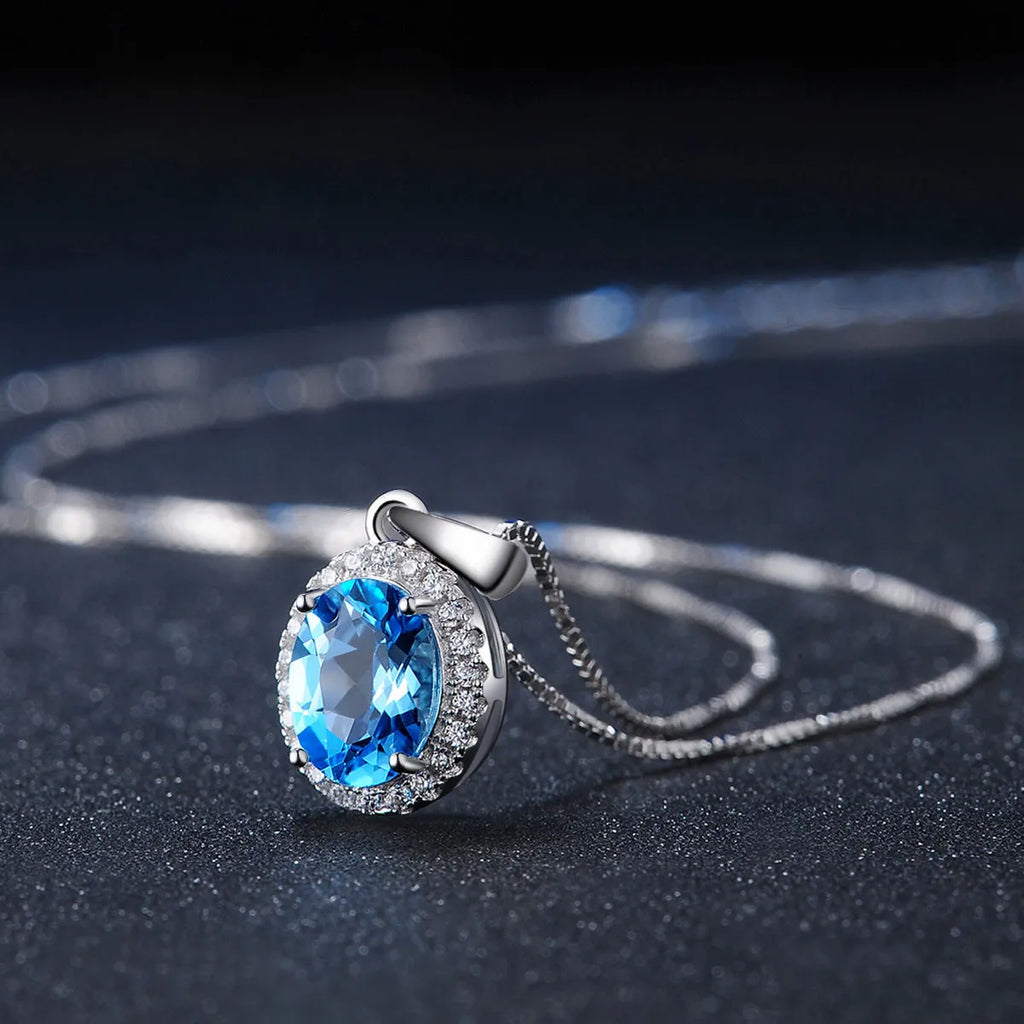 925 sterling silver jewellery set with blue topaz gems including geometric pendant necklace, earrings, ring, and bracelet.