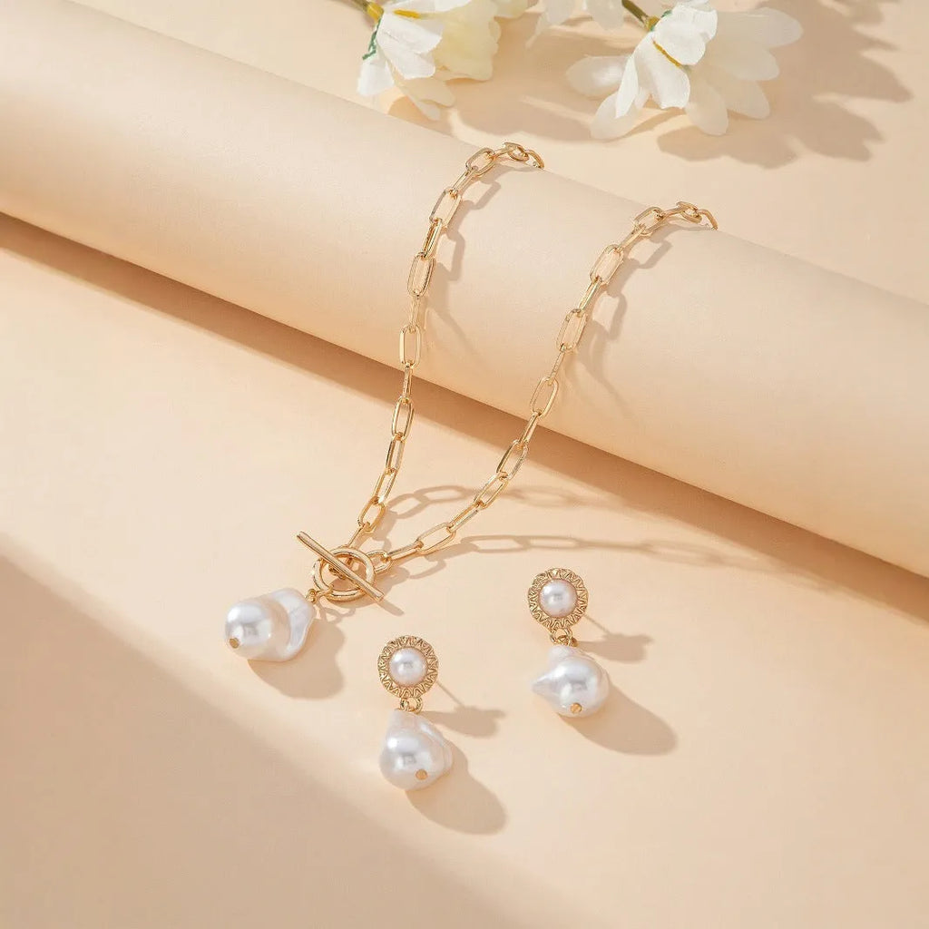 Gold tone baroque pearl pendant necklace and matching ear stud set on display