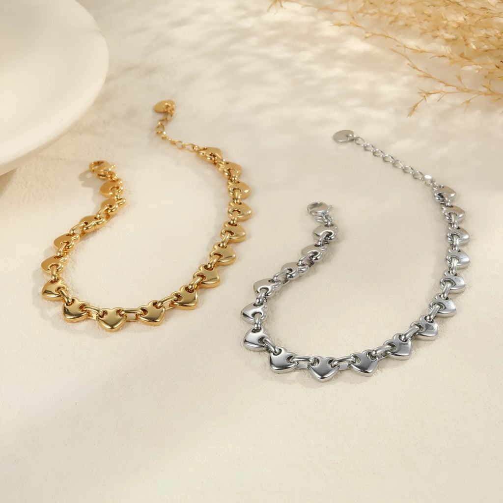 Hollowed-out stainless steel heart bracelet in gold finish on a wrist.