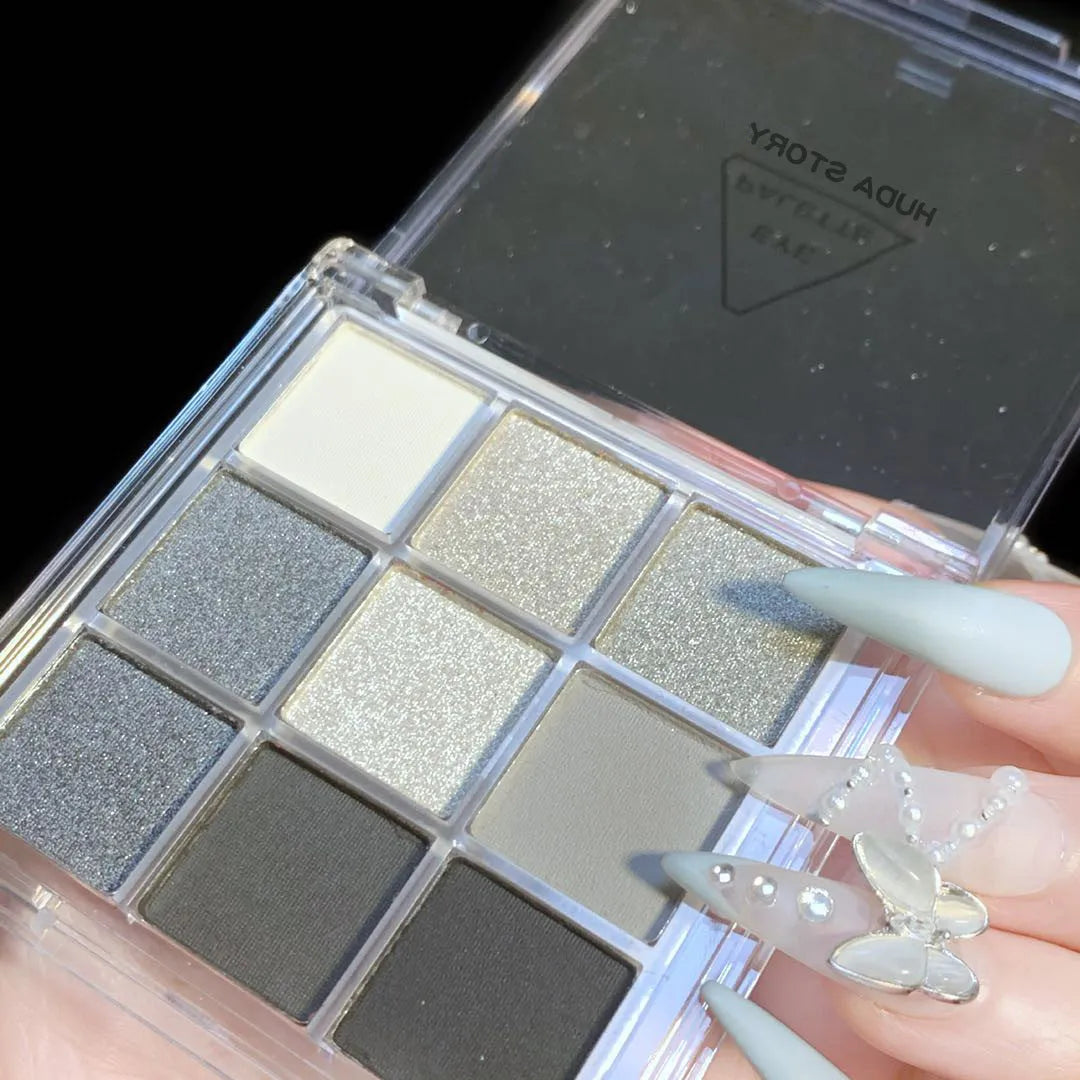 Nine-colour smoked eye shadow palette showing pressed powder shades including white, silver, black, and grey.