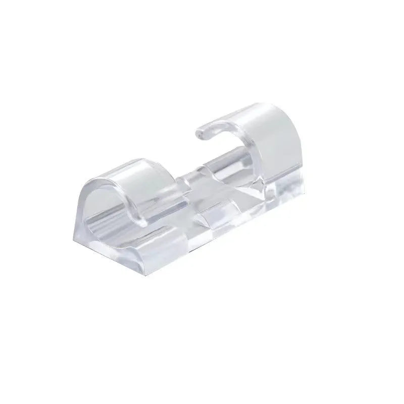 Transparent plastic self-adhesive wire holder routing snap clip on a desk surface with a white cable inserted