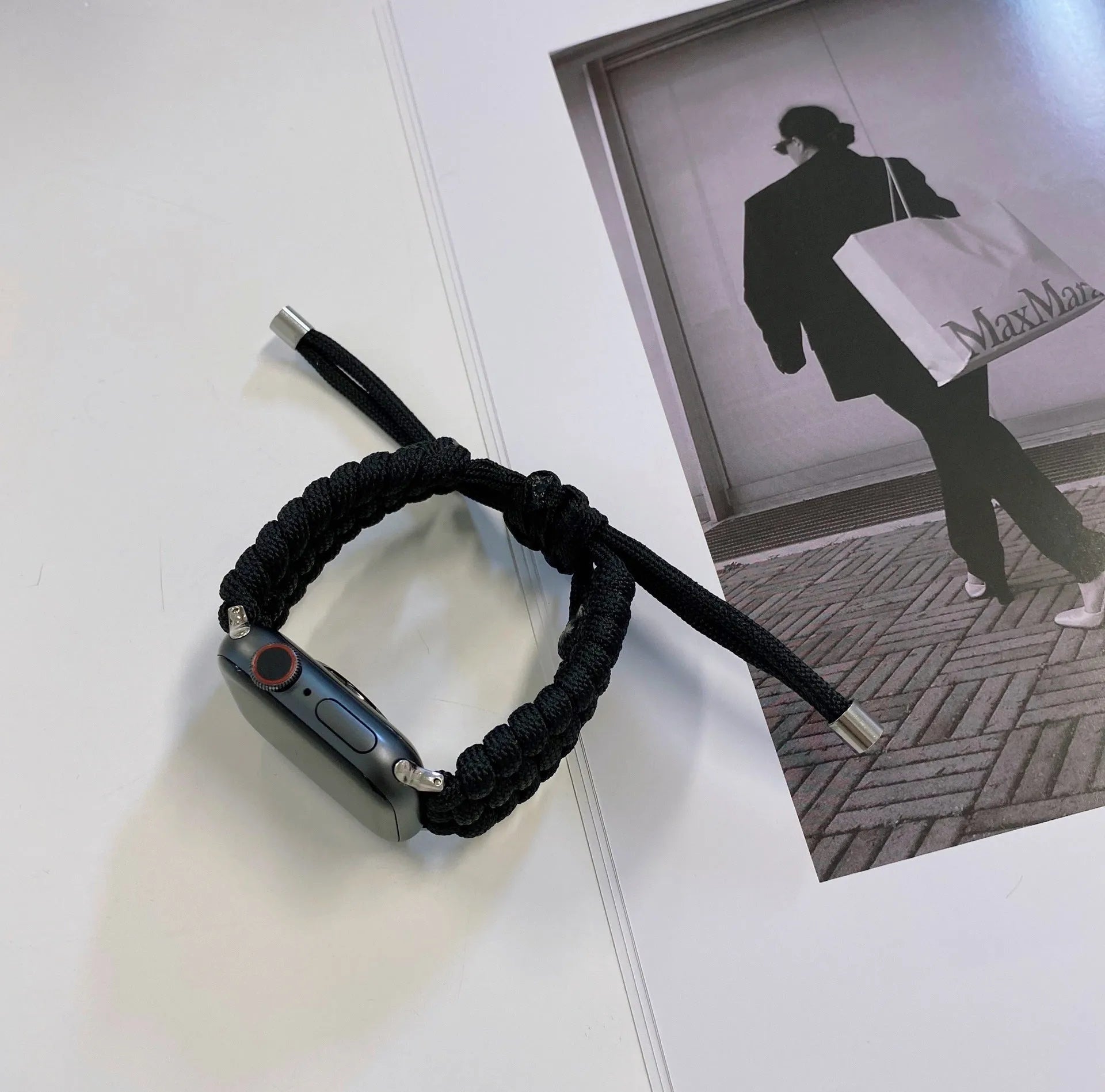 Paracord braided smartwatch strap in black shown next to an Apple Watch.