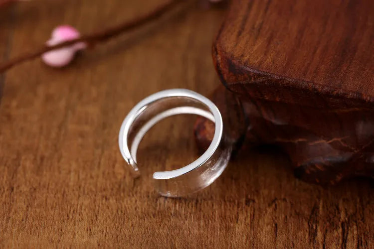 Geometric open ring in frosted sterling silver on a neutral background, showing adjustable opening.