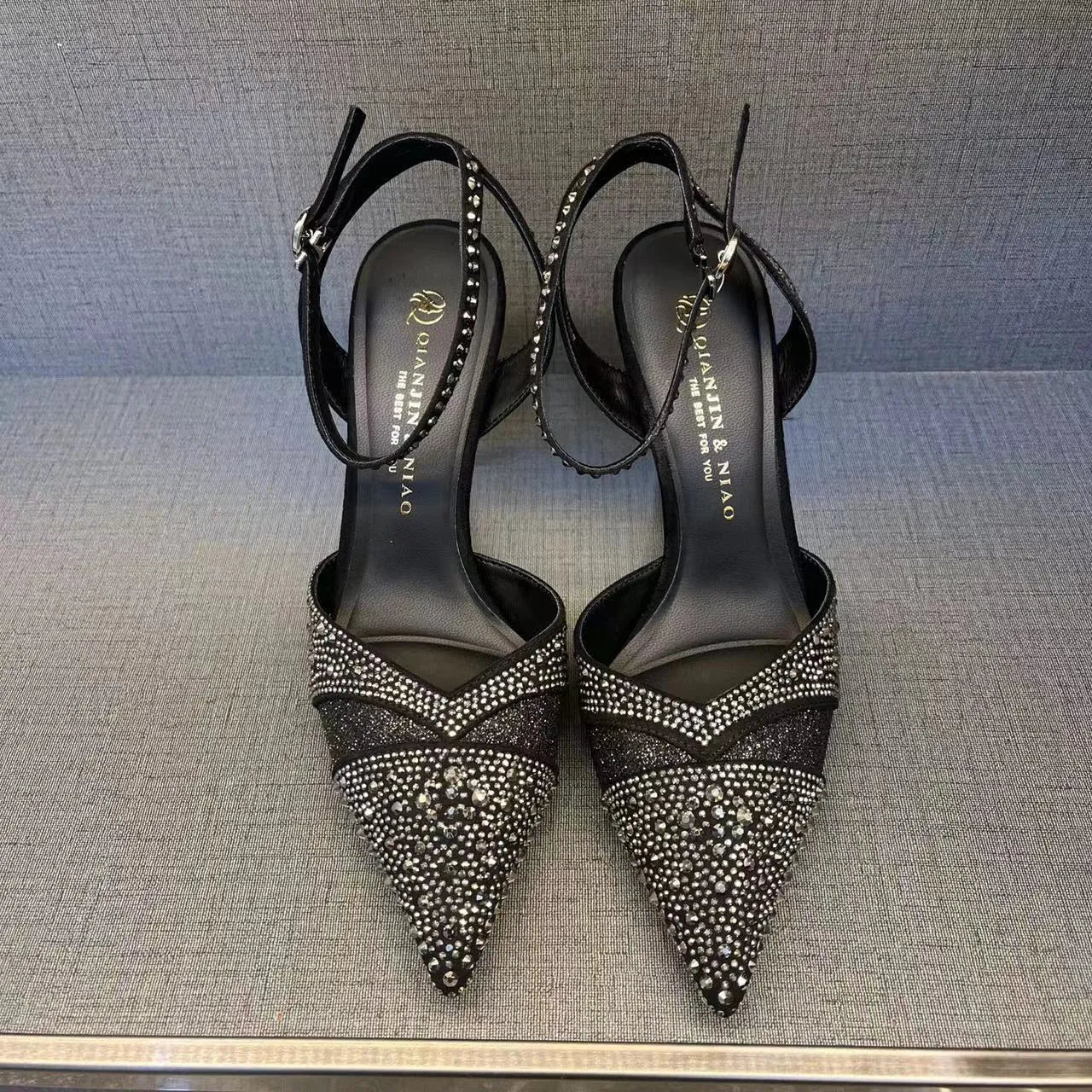 Women's black hollow high heel with stiletto heel, pointed toe, and red sole on a plain background.