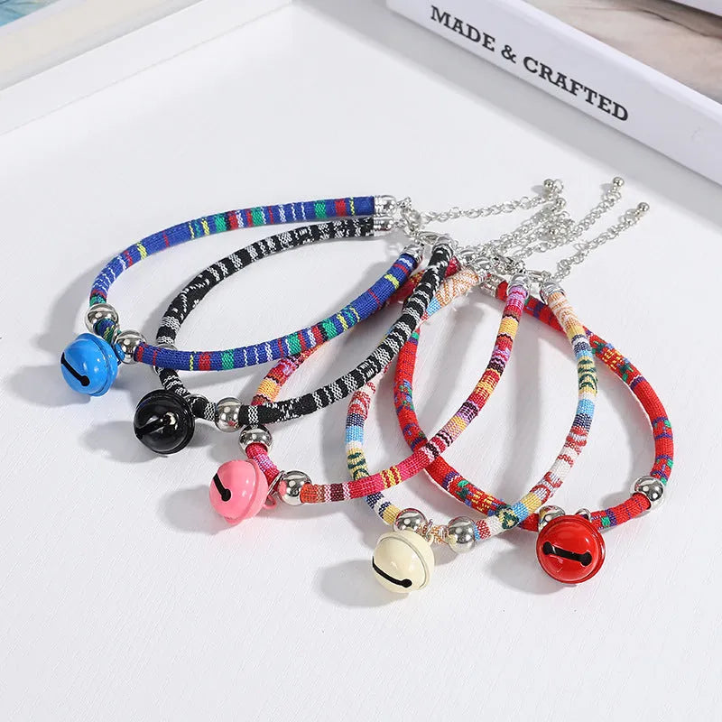Colourful adjustable pet collar with ethnic patterns and a small metal bell attached, shown in multiple colour options.