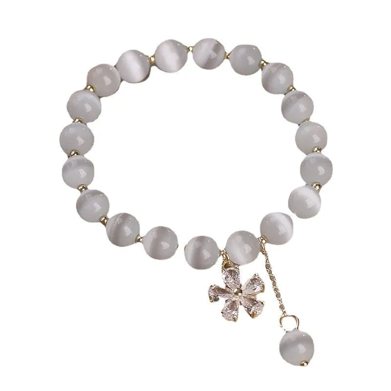 Women's white cat's eye crystal bracelet with floral tassel design and safety buckle pendant