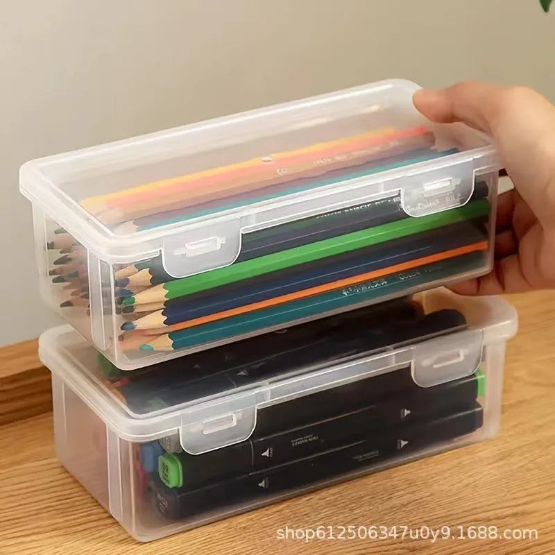 Clear plastic stationery storage box full of coloured pencils and drawing tools on a table.