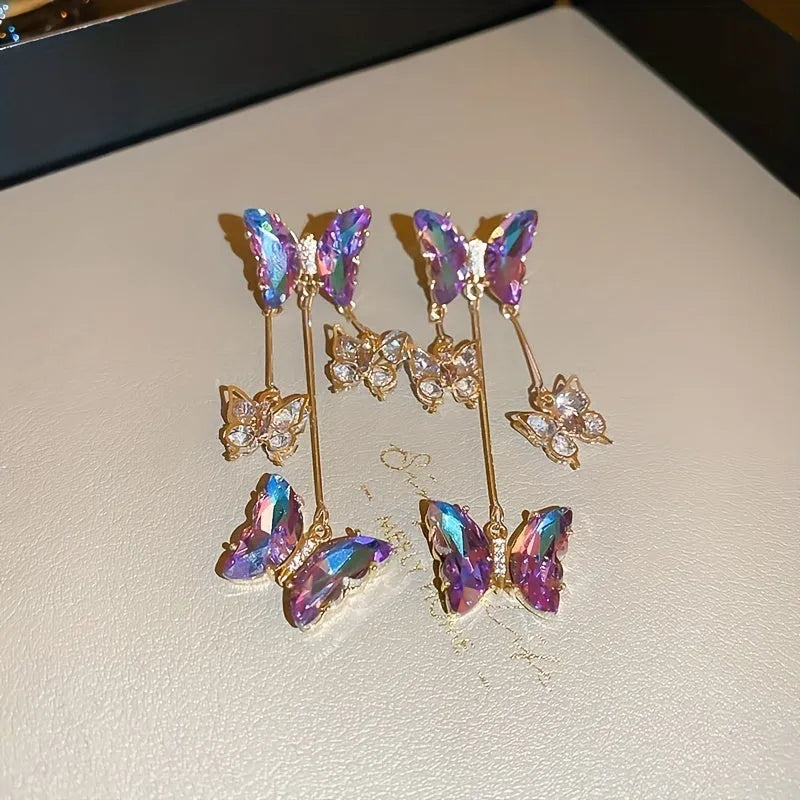 Close-up of women's silver needle blue purple butterfly alloy earrings with crystal flowers and a dangle tassel.