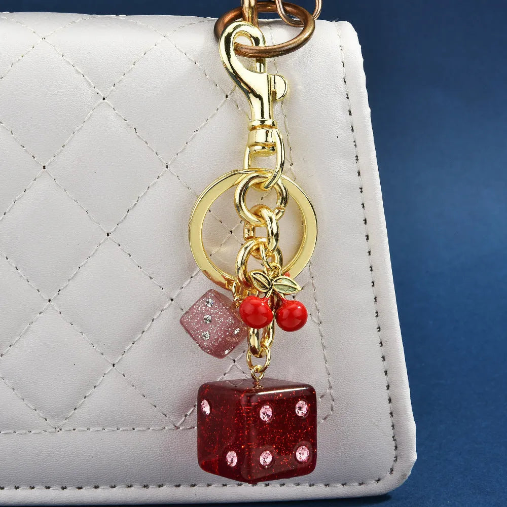 Square metal keychain pendant with a vintage red and white cherry dice pattern.