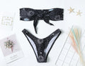 Black one-piece swimsuit with bikini print, featuring a split tube top and backless design.
