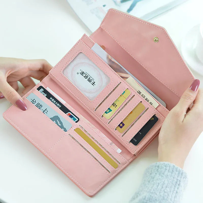 Women's black tri-fold PU leather wallet with buckle fastener showing open compartments.