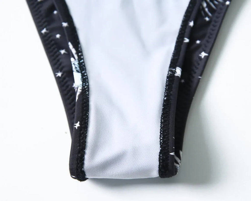Black one-piece swimsuit with bikini print, featuring a split tube top and backless design.