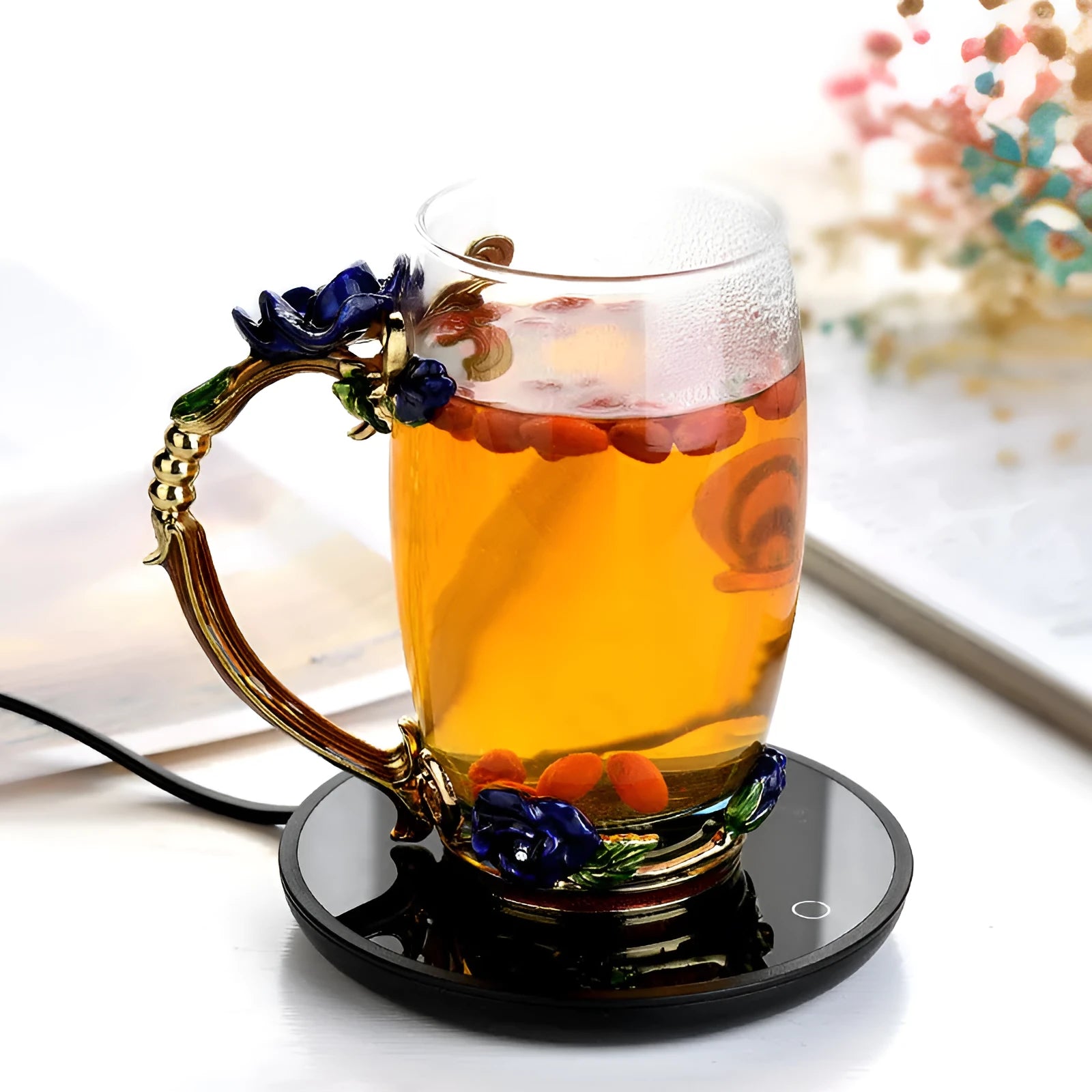 Black circular mug warmer with temperature switch, 12cm in diameter, on a desk next to a coffee cup.