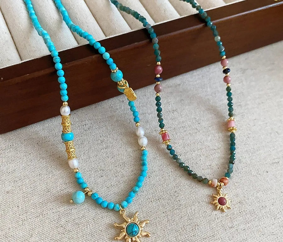 Freshwater pearl necklace with sun motif stone pendant on an adjustable clavicle chain.