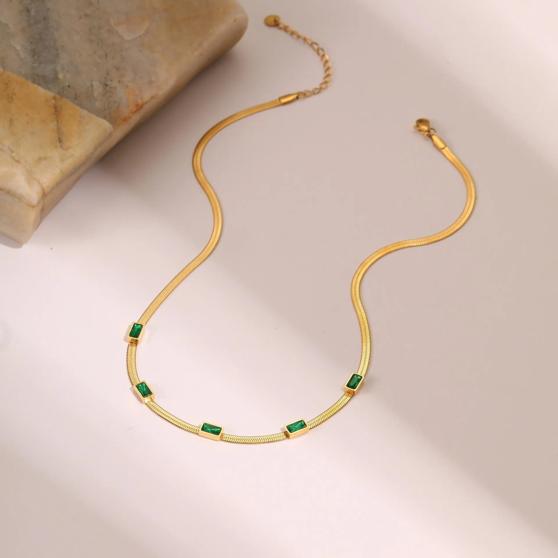 Gold geometric square zircon pendant on a stainless steel flat snake chain necklace.