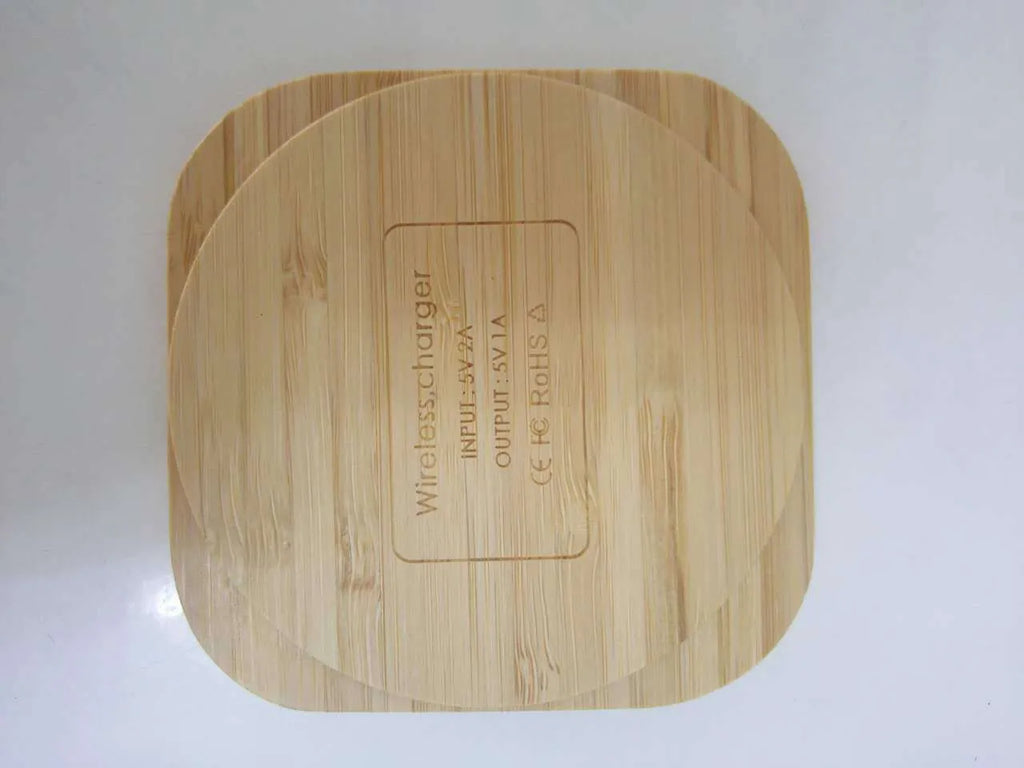 Square brown wooden bamboo wireless charging pad for phones on a desk