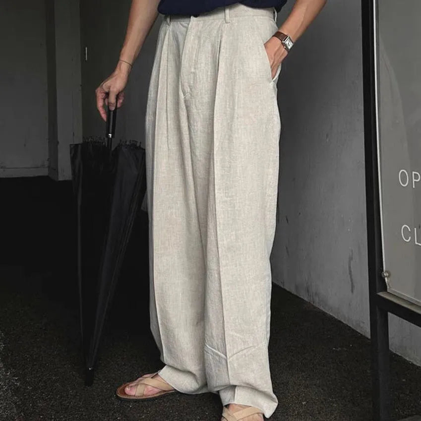 Men's lightweight apricot coloured loose-fit linen trousers laid flat, showing zip fly and relaxed leg style.