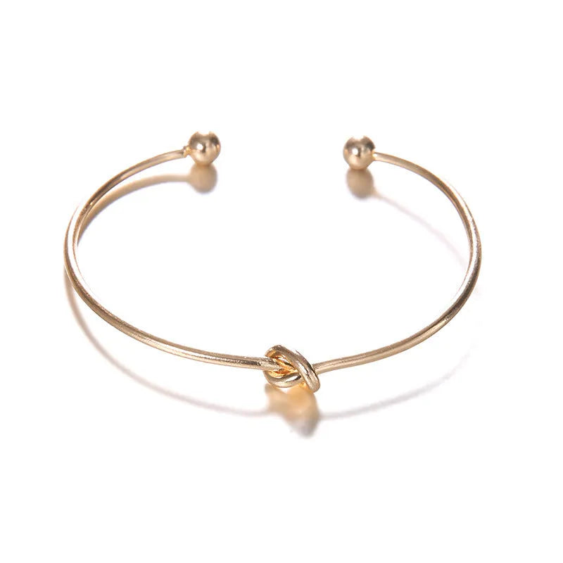 Gold-coloured women's vintage cuff bracelet with an arrow and knotted design motif.