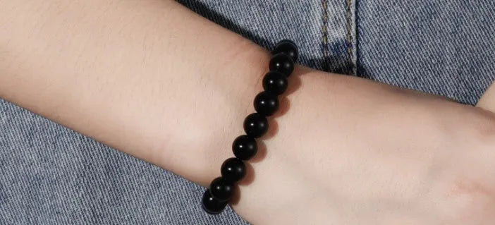 Women's black onyx agate beaded bracelet with geometric design and elastic cord.