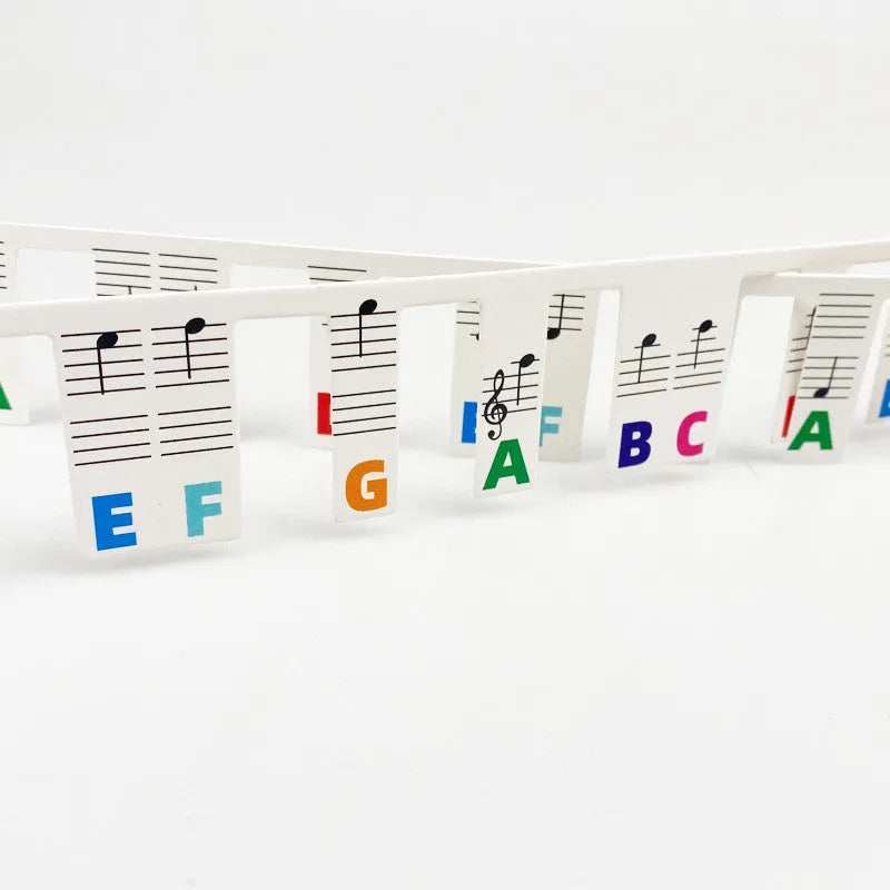 Set of 88 key piano keyboard stickers showing black note and colour note bar designs on white cardboard.