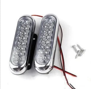 Two white car LED auxiliary lights with iron brackets and screws on a dark background