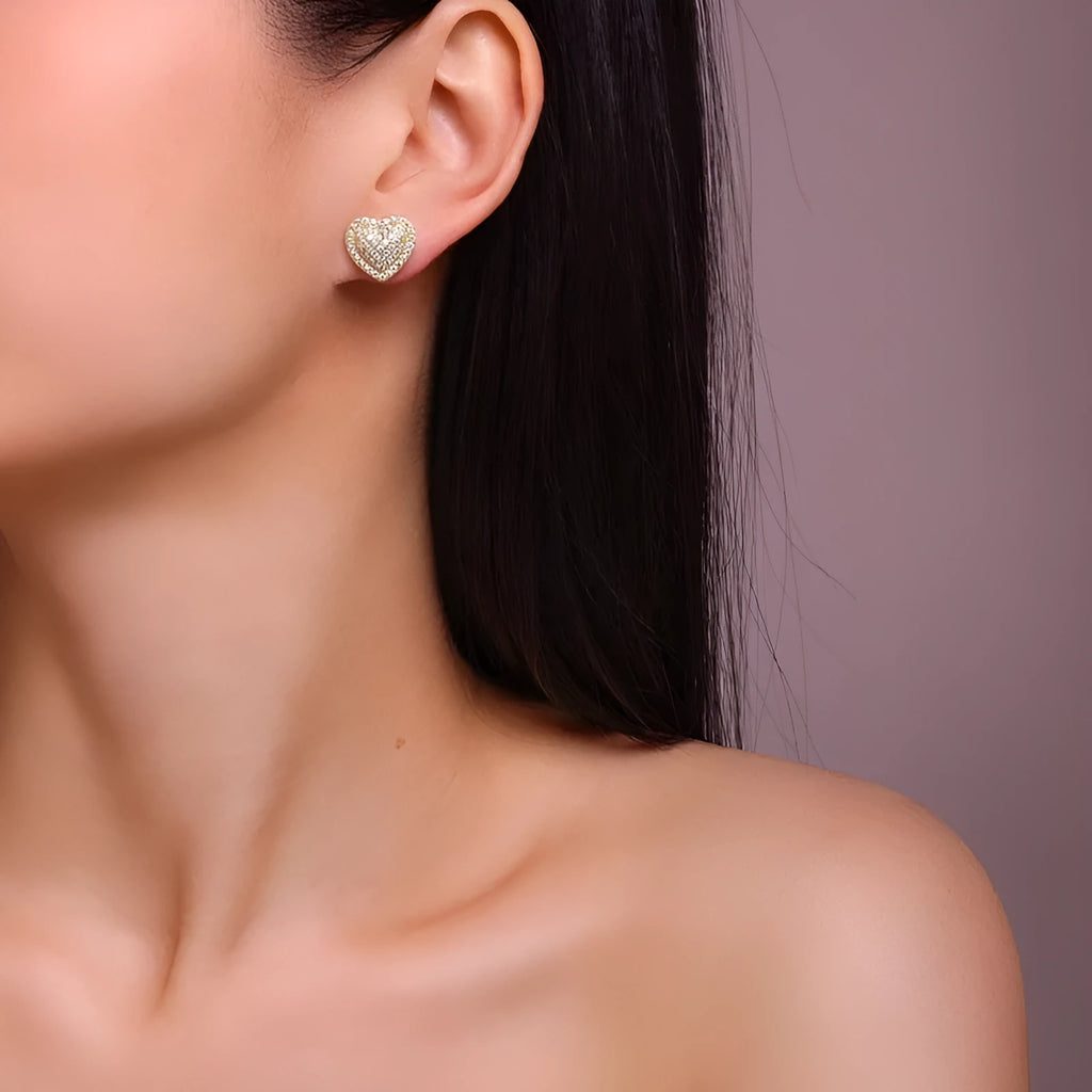 Golden heart-shaped stud earrings with moissanite centre on silver background