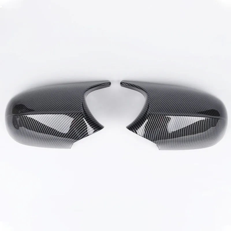 A pair of black and carbon pattern ABS plastic rearview mirror housing shells for a BMW 3 Series E90.