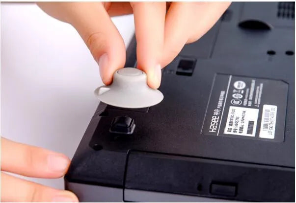 Four grey plastic non-slip laptop cooling pads, two large and two small, on a desk.