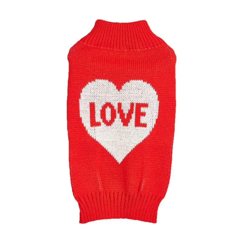 Small dog wearing a red knitted jumper with a white love heart motif on the chest.