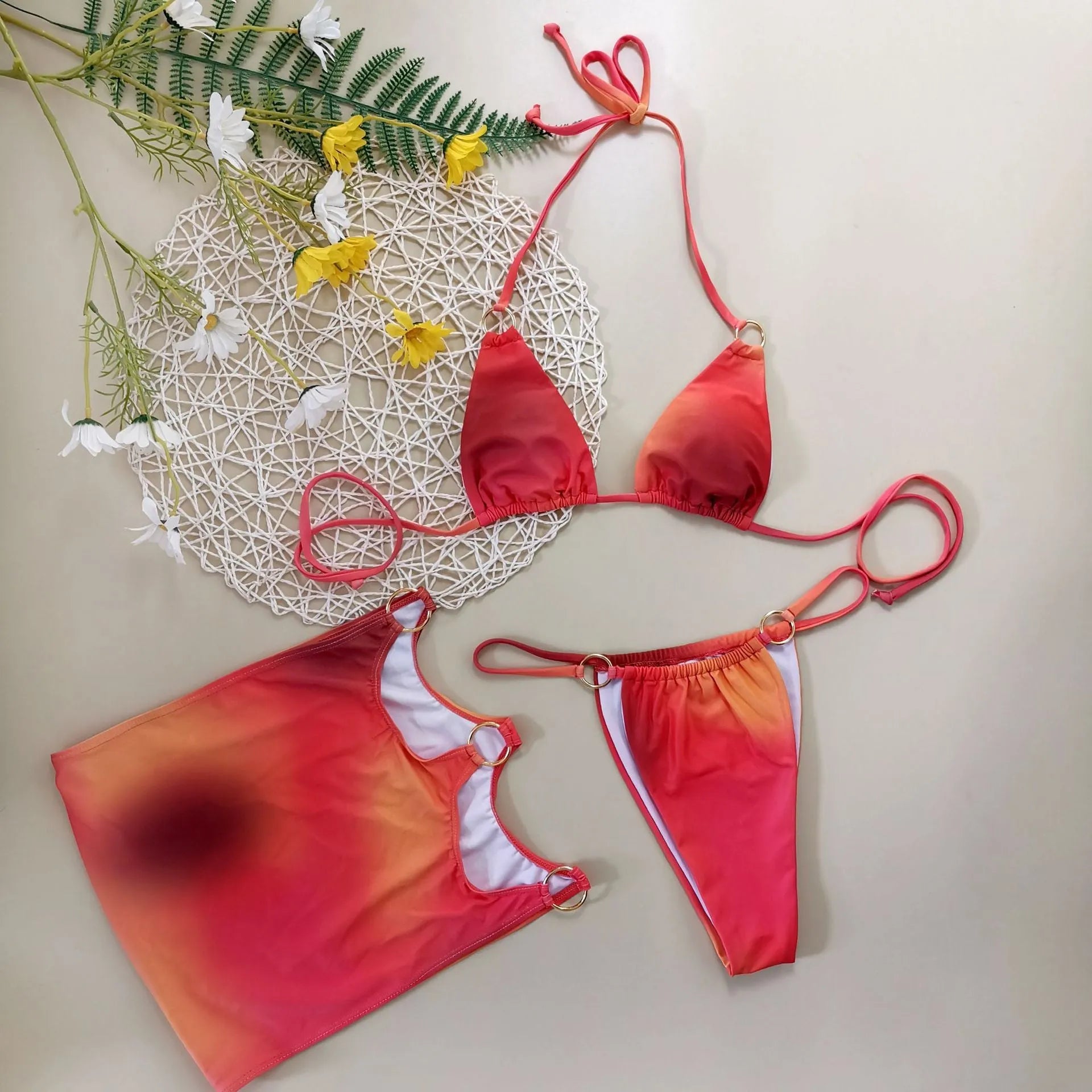 Solid colour tie-dye gradient three-piece halter bikini swimsuit set with skirt on hanger.