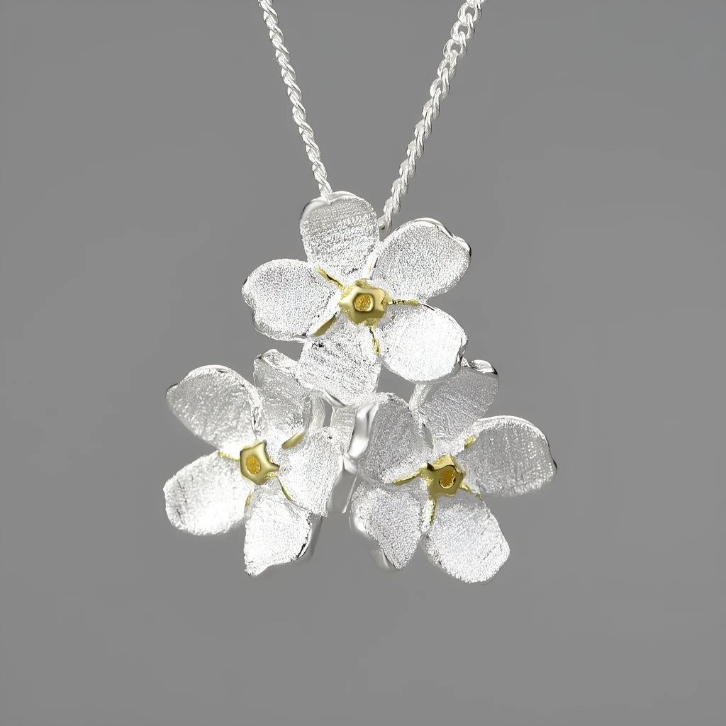 Hand-designed sterling silver forget-me-not flower pendant in pastoral style on a dark background.