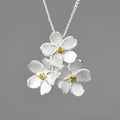 Hand-designed sterling silver forget-me-not flower pendant in pastoral style on a dark background.
