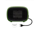 Mini green PTC ceramic fan heater on a desk showing compact size