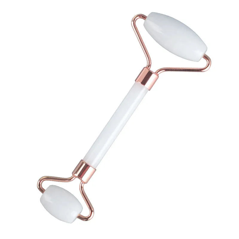 White jade facial roller and Gua Sha scraping board set on a plain surface.