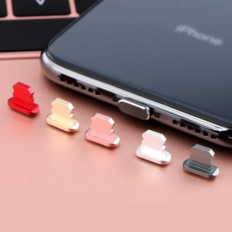 Aluminium alloy iPhone charging port dust plug in rose gold colour next to an iPhone.