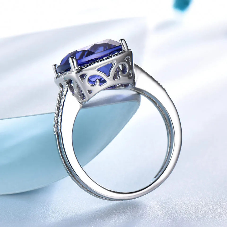 Blue tanzanite gemstone set in a sterling silver women's ring on a grey background