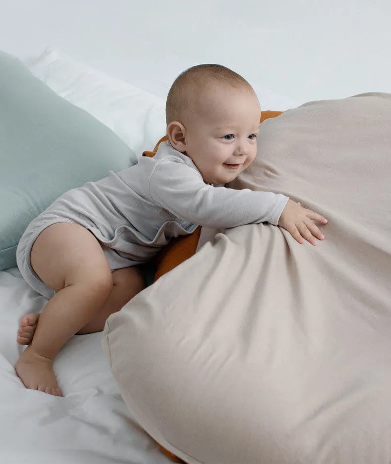Beige portable cotton baby nest crib for infants on a neutral background.