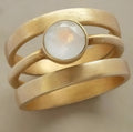 Gold geometric titanium steel ring with white chalcedony stone in a hollow micro-inlaid setting.