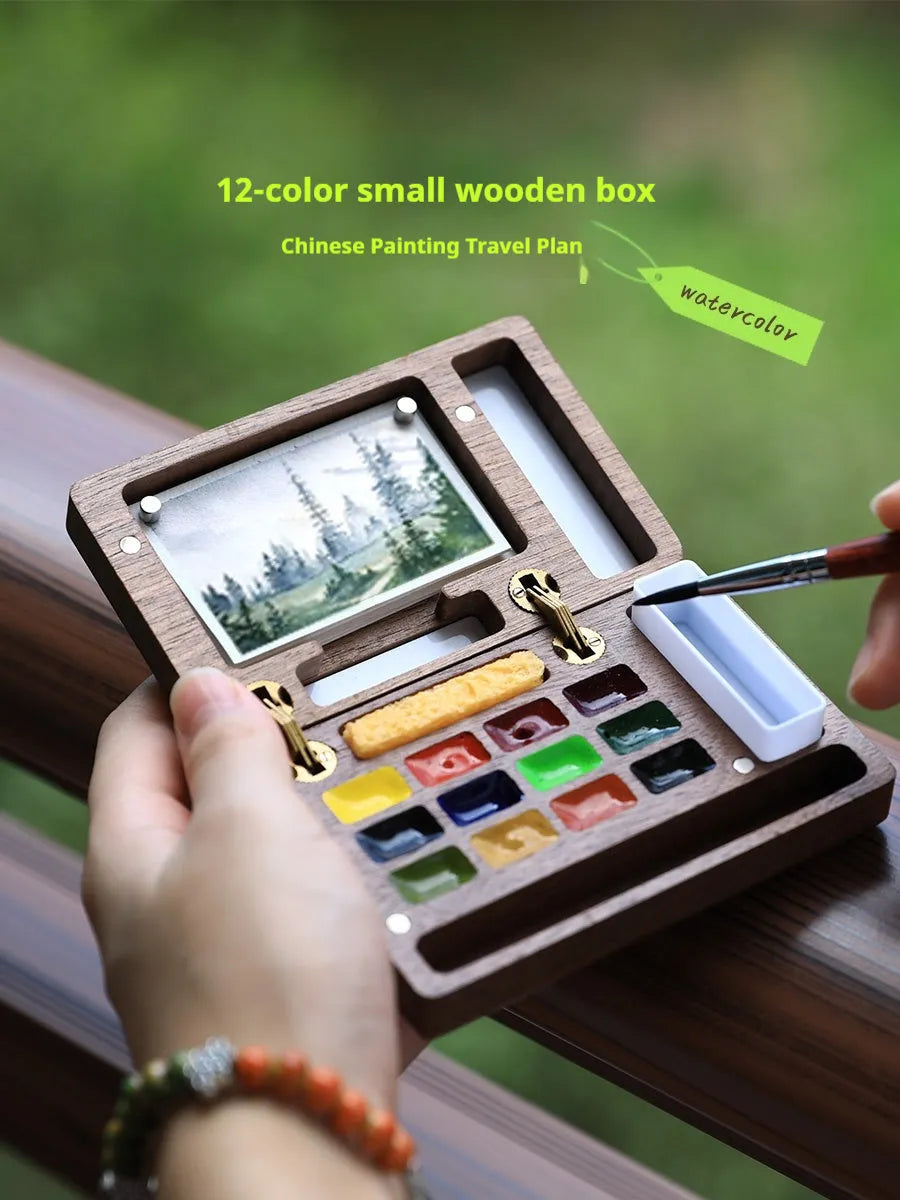 Miniature walnut wood watercolour paint box open to show 24 half-pan pigments and mixing areas