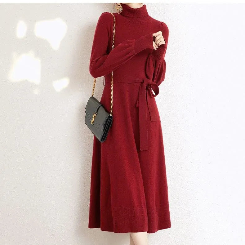 A woman wearing a rose red turtleneck long-sleeve knit dress with an elastic waist and loose hem.