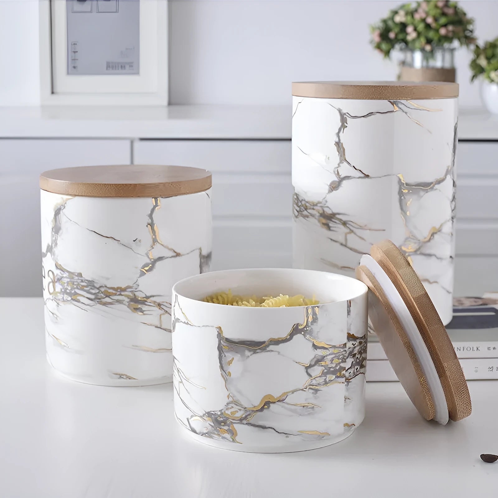 Three marbled ceramic jars with bamboo lids in large, medium and small sizes on a kitchen counter