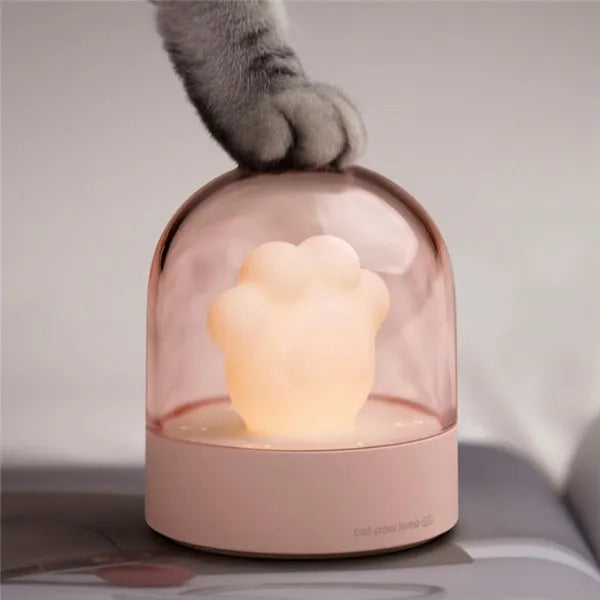 Grey cat paw shaped musical night light with USB charging cable on wooden desktop