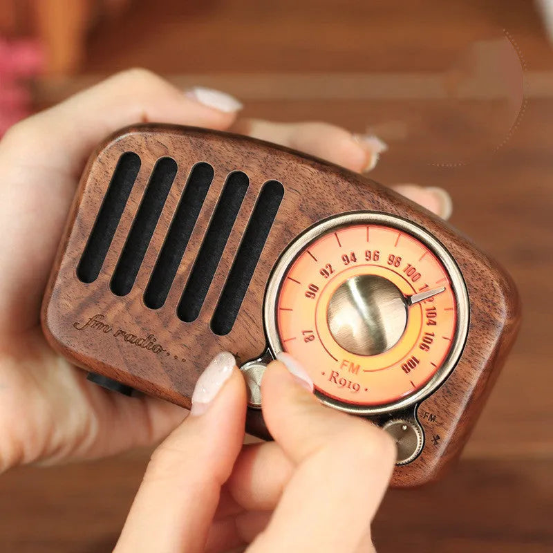 Retro wooden wireless mini speaker in cherry wood finish on a wooden table.