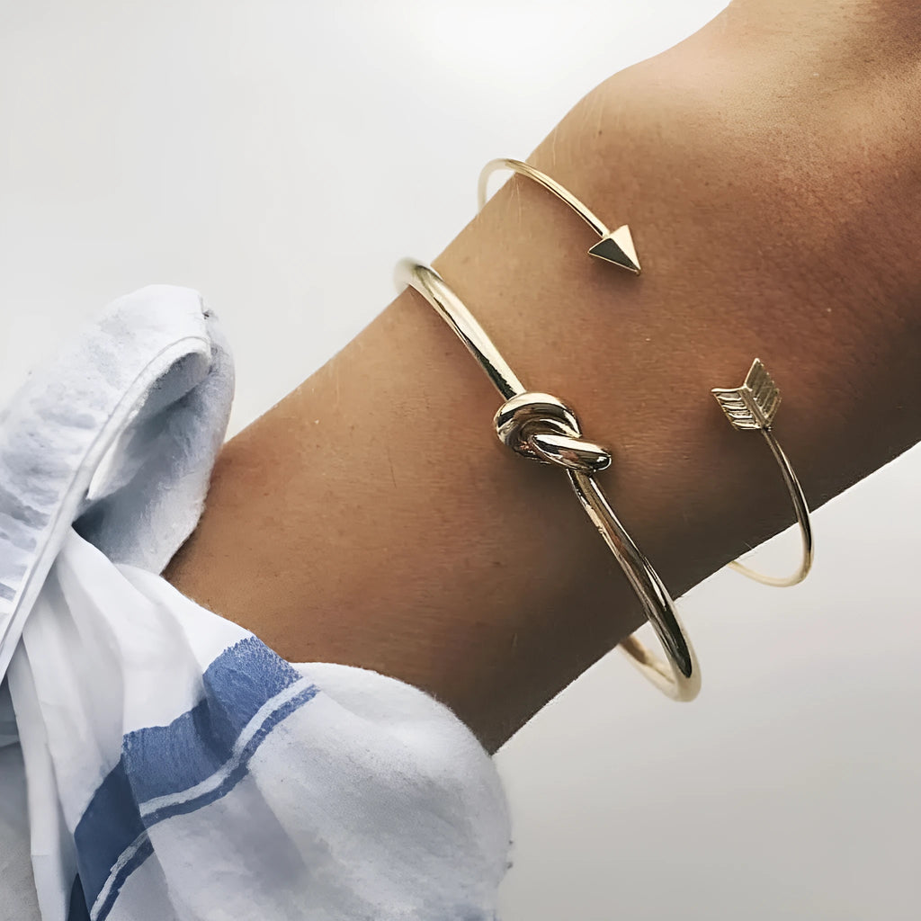 Gold-coloured women's vintage cuff bracelet with an arrow and knotted design motif.