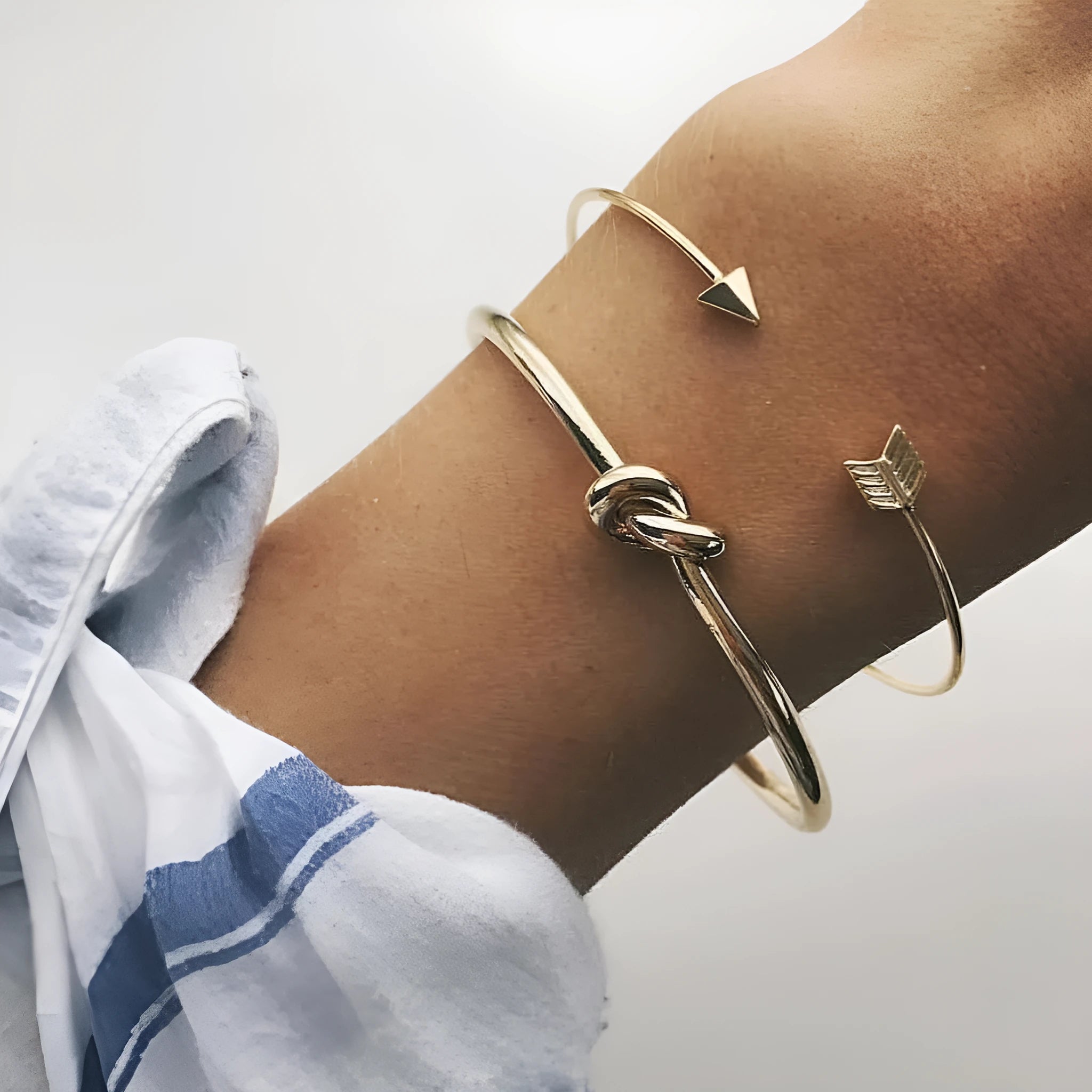 Gold-coloured women's vintage cuff bracelet with an arrow and knotted design motif.