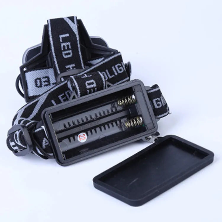 Fixed focus camping head torch with long range beam on a headband, shown with its rechargeable battery and charger.