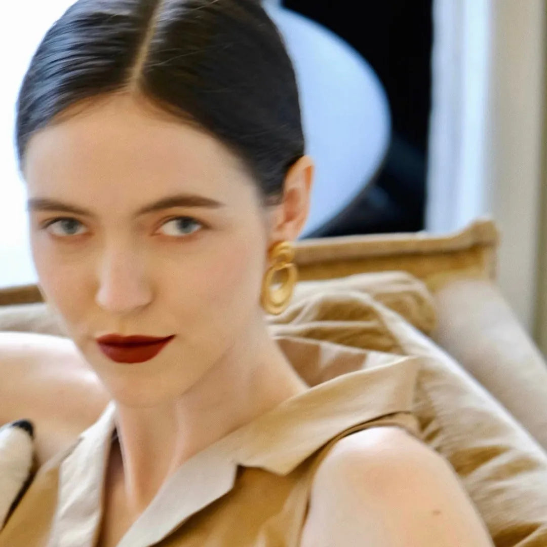 A pair of gold-toned double circle earrings with a textured quicksand finish on a copper base.